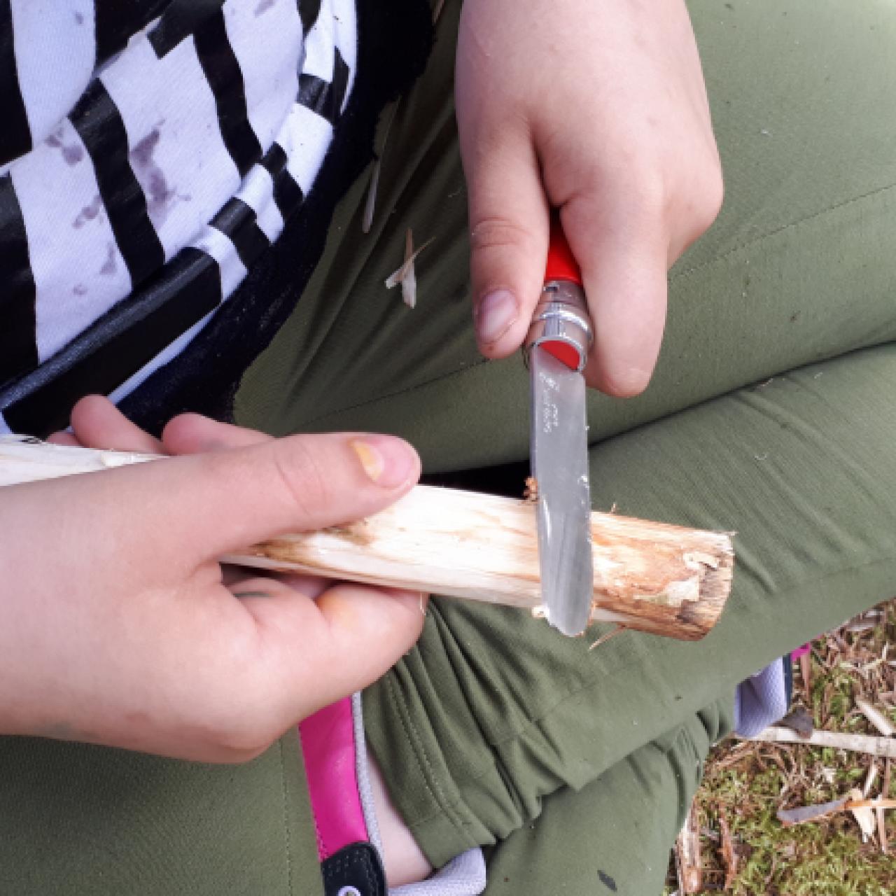 Bub mit Taschenmesser beim Schnitzen